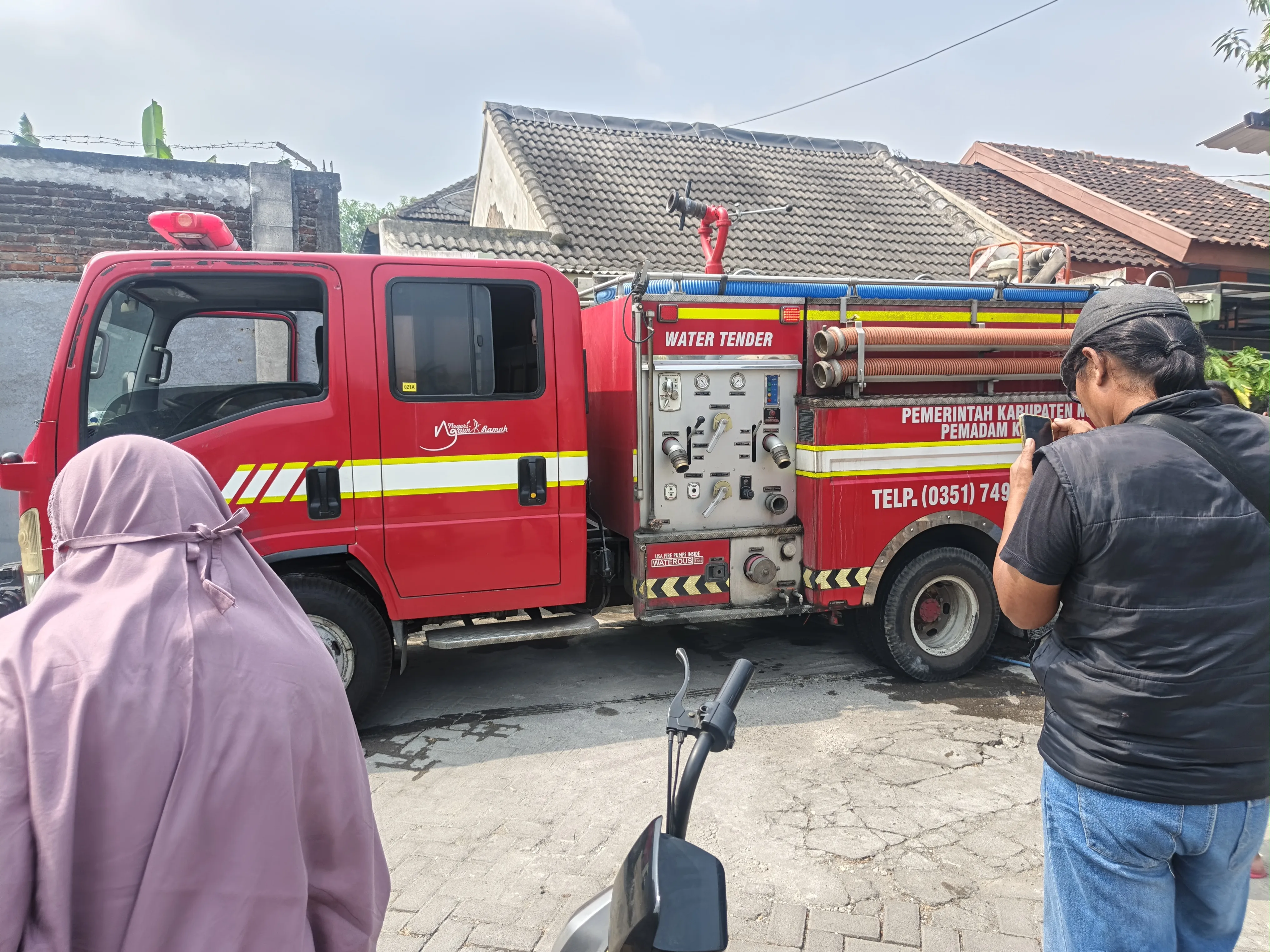 Petugas Damkar Kabupaten Ngawi mengerahkan dua unit mobil pemadam untuk menangani kebakaran rumah di Perumahan Loka Wiyata yang diduga dipicu kompor gas masih menyala.